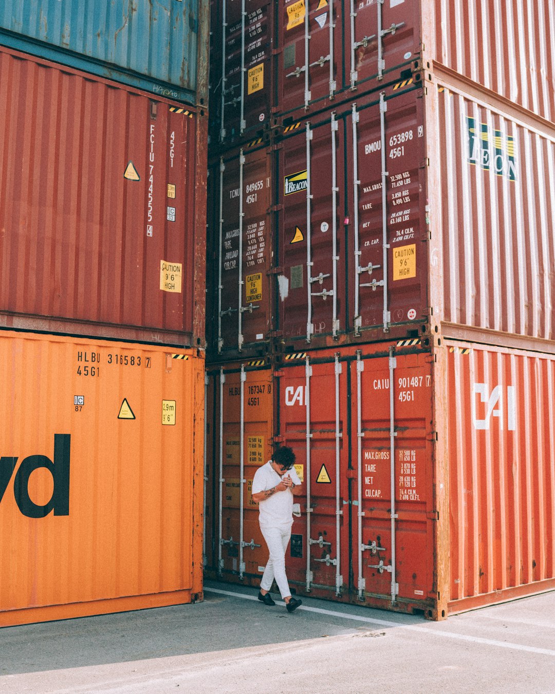 a-man-standing-in-front-of-a-stack-of-shipping-containers-fbre-7tbyxq