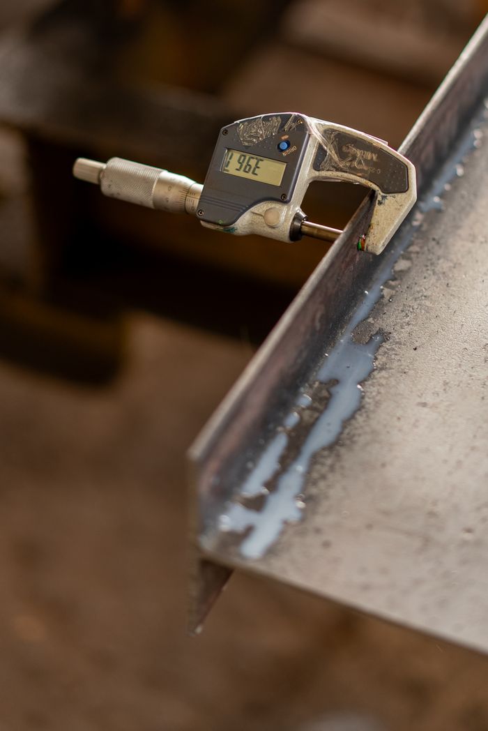 ours-journey Close-up of a digital micrometer measuring the thickness of a metal sheet, showcasing industrial precision.